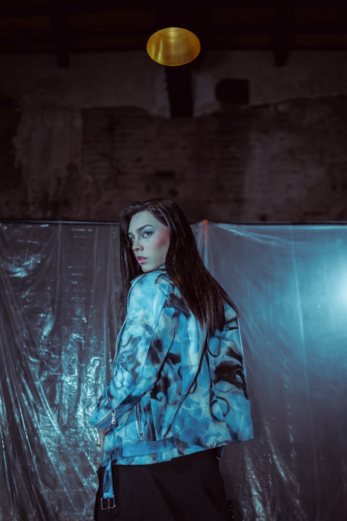 Stylish woman in a vibrant blue jacket in a moody urban setting.